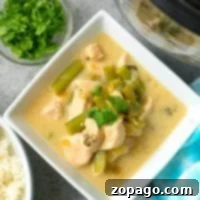 Creamy coconut chicken with a side of rice and fresh herbs nearby, all crafted effortlessly in the pressure cooker.