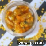 Golden Goo 2 A jar of golden, glittery gummy bears that look like honey slime, with sequins on a black and white striped background.