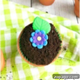 A close-up of a beautifully decorated flower pot cupcake in a small terracotta pot, ready to be enjoyed.