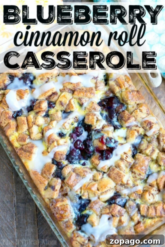 This easy cinnamon roll breakfast casserole with blueberries is just amazing! Served for brunch or on Christmas morning it is a great way to make cinnamon rolls into a fruit casserole that everyone will love. Feeds 12 and costs under $10 to make which is a winner in my book! #cinnamonroll #casserole #breakfast #blueberry #fruit #easy A stunning Pillsbury Cinnamon Roll Breakfast Casserole, adorned with icing and fruit, perfect for sharing.