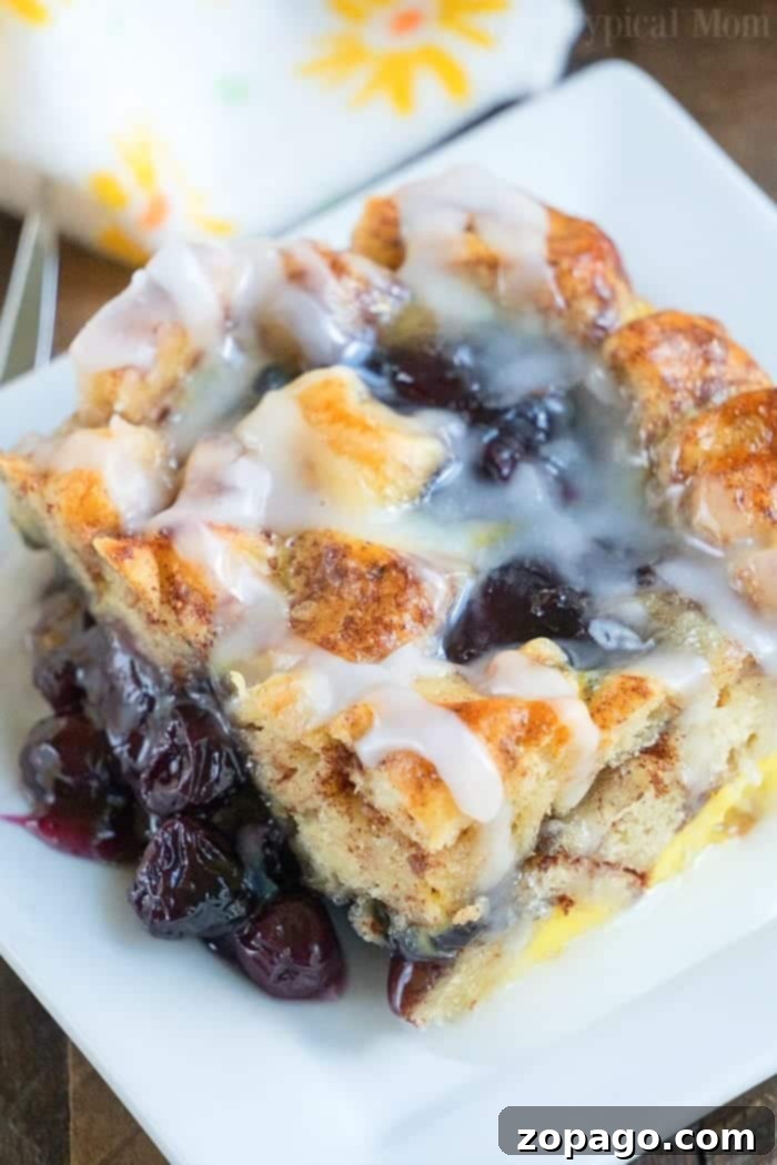 Cinnamon roll breakfast casserole with blueberries is just amazing! Served for brunch or on Christmas morning it is a great way to make cinnamon rolls into a fruit casserole that everyone will love. Feeds 12 and costs under $10 to make which is a winner in my book! #cinnamonroll #casserole #breakfast #blueberry #fruit #easy Close-up of a delightful Cinnamon Roll Breakfast Casserole, with golden crust and generous frosting.