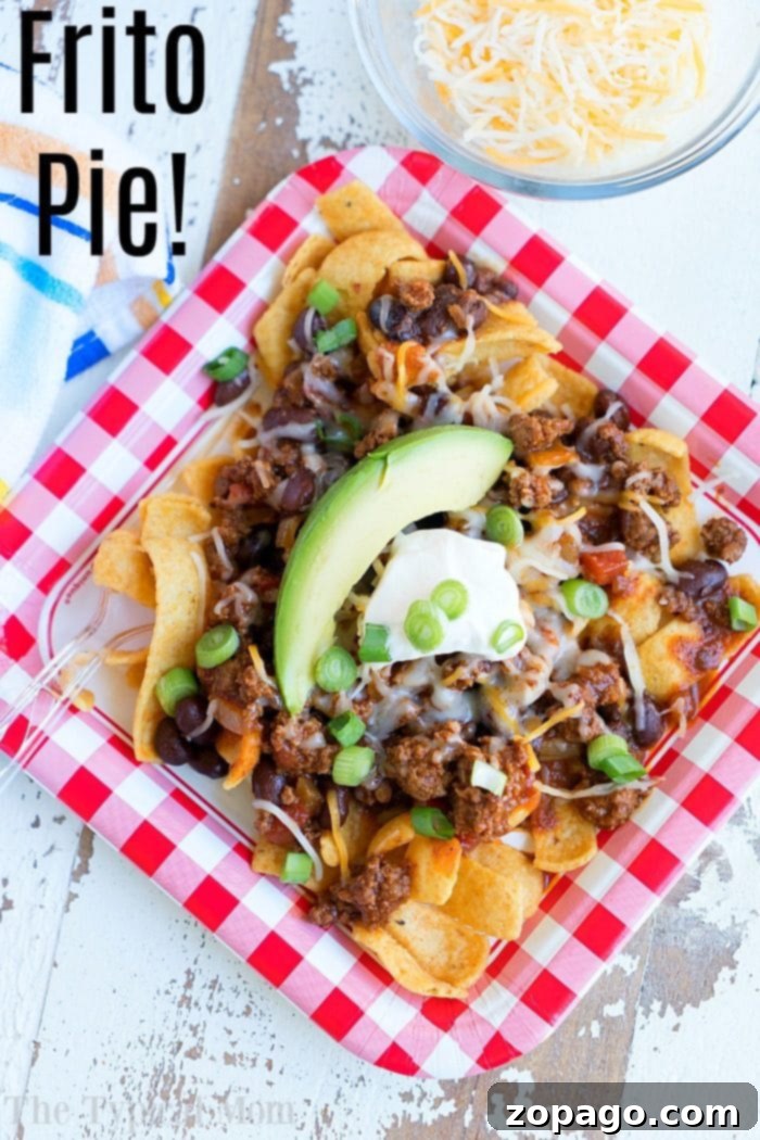 Frito chili pie recipe, presented beautifully with a generous amount of toppings, a true comfort food delight. #fritochipie Frito chili pie recipe, a close-up shot of a serving topped with sour cream, avocado, and green onions.
