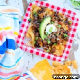 A plate of nachos topped with avocado, sour cream, and green onions sits next to a Fritos bag and colorful napkin, reminiscent of an Instant Pot Frito chili pie recipe.
