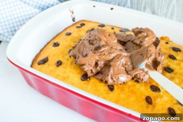 Close-up of a chocolate poke cake with visible holes filled with ganache, demonstrating the technique for how to make a poke cake extra moist.