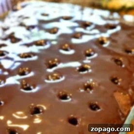A glass baking dish with a rich chocolate cake covered in glossy glaze showcases evenly spaced holes, highlighting a perfect poke cake.