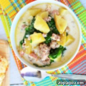 Easy Instant Pot Zuppa Toscana 7 A bowl of creamy pressure cooker zuppa Toscana with potatoes, sausage, and kale rests on a colorful tablecloth beside a spoon.