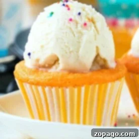 A delightful vanilla cupcake, created using a soda cake mix, topped with a scoop of ice cream and colorful sprinkles on a pristine white plate.