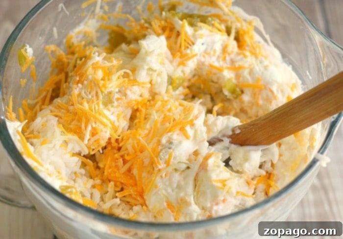 Velvety Green Chile Rice 3 A clear bowl of cheesy green chile casserole mixture with a wooden spoon, infused with the vibrant zest of green chile rice.