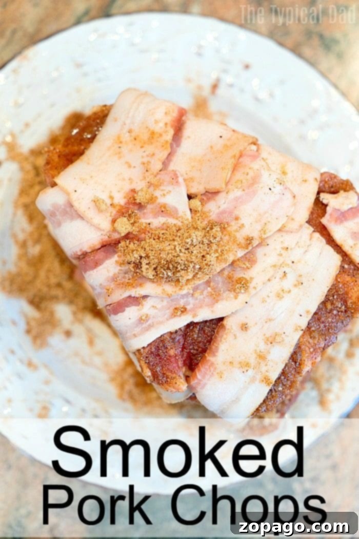Smoked bacon wrapped pork chops are incredible and you have to make them tonight! Pair with our smoked baked potatoes for the perfect meal. #smoked #smoker #porkchops #bacon #pork #rub #smokerrecipes #thetypicalmom A wooden board displaying three bacon-wrapped smoked pork chops and four baked potatoes in front of a smoker grill.