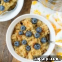 A bowl of pressure cooker breakfast quinoa is topped with fresh blueberries and a sprinkle of cinnamon, sitting next to a vibrant yellow floral napkin.