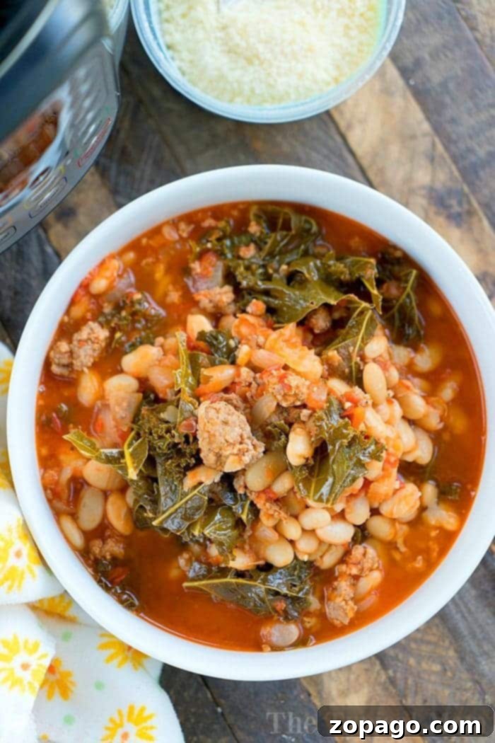 Pressure cooker sausage soup is packed with flavor and can be made with or without kale. Using canned or dry beans it's the perfect dinner. A bowl of hearty Italian sausage soup with beans and kale, prepared effortlessly in a pressure cooker, sits on a wooden table next to freshly grated cheese.