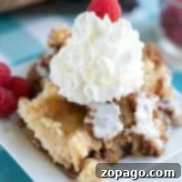 A delightful apple spice dump cake on a plate with whipped cream and a raspberry.