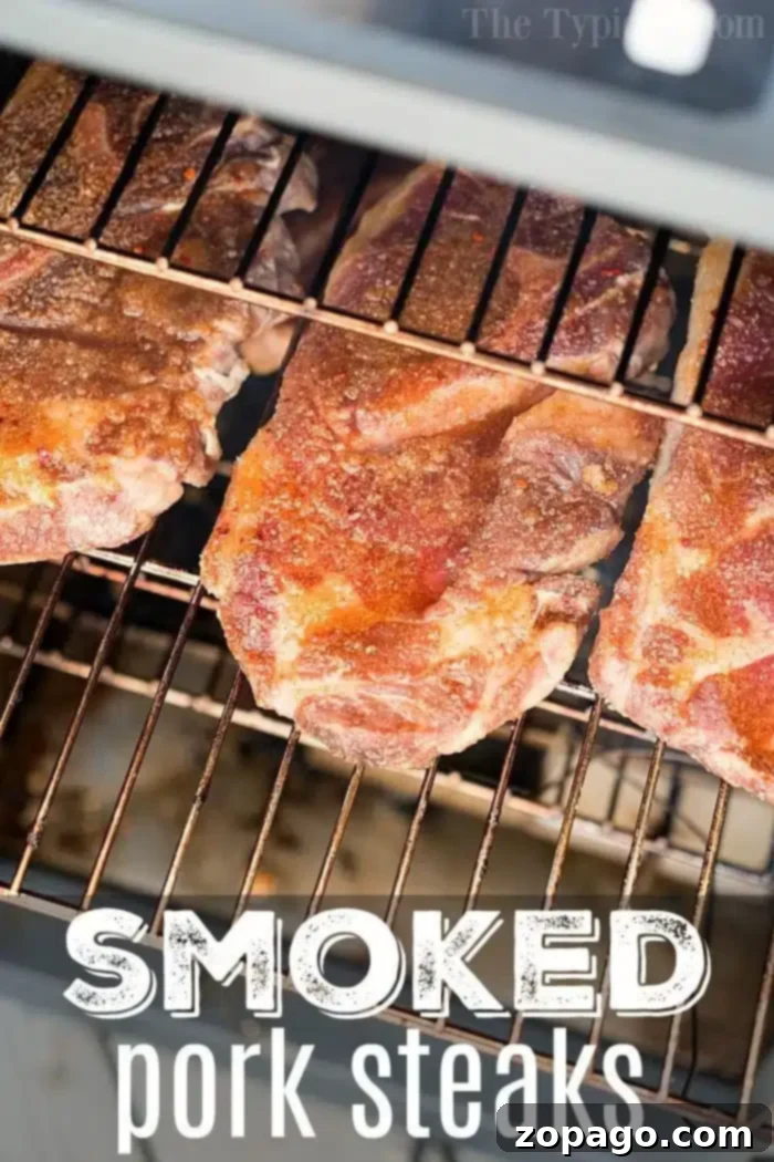 Smoked pork steaks with an amazing dry rub make a great dinner! Full of flavor and easy to make. #smoked #smoker #pork #steaks #dryrub #smokerrecipes #smokedpork Four large, perfectly seasoned smoked pork steaks sizzling on a wire rack inside a smoker, labeled 'SMOKED pork steaks.' The meat looks incredibly tender and ready to be enjoyed.