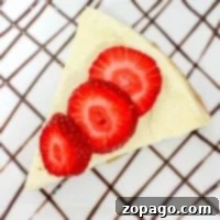 A slice of cheesecake made from an instant pot cheesecake recipe, topped with strawberries and served on a plate drizzled with chocolate sauce in a crisscross pattern.