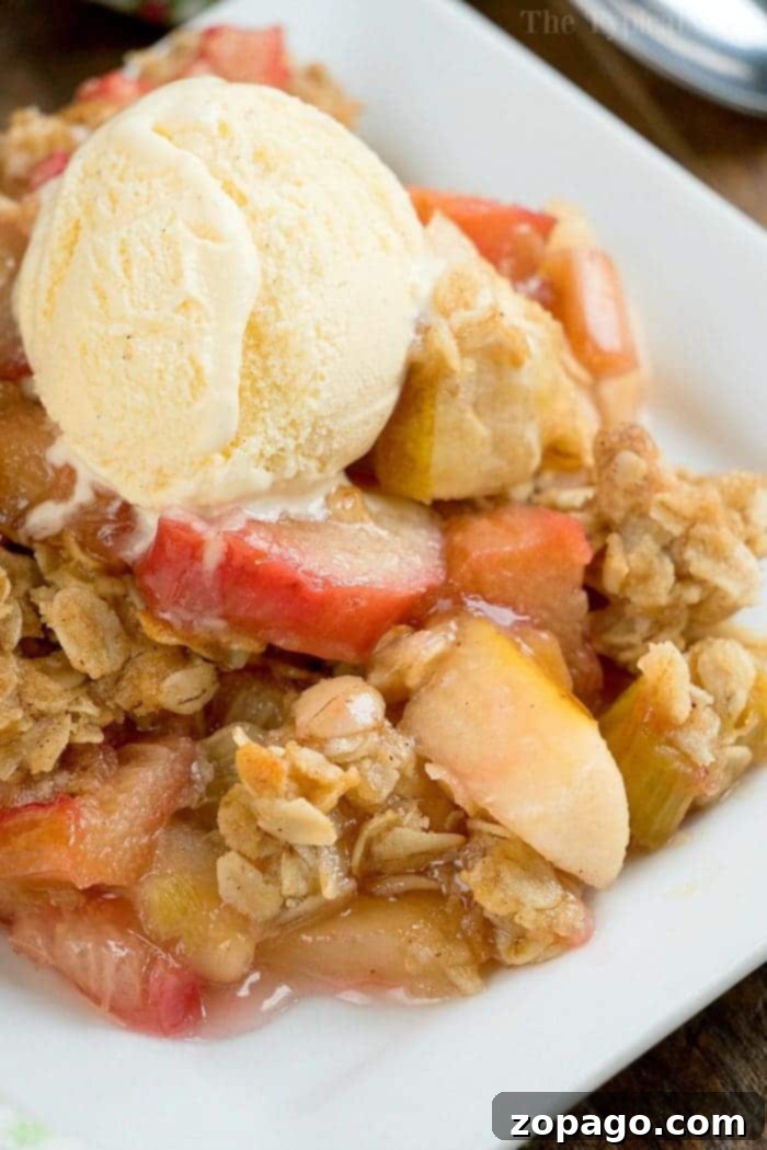 Apple Rhubarb Crisp Serving Suggestion A generous slice of warm apple rhubarb crisp on a plate, garnished with a sprig of mint.