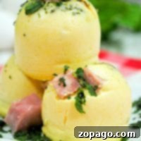Three steamed egg bites, reminiscent of Starbucks' sous vide eggs, are stacked on a white plate, garnished with chopped parsley and small pieces of ham.