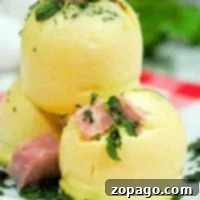 Three steamed egg bites, reminiscent of Starbucks' sous vide eggs, are stacked on a white plate, garnished with chopped parsley and small pieces of ham.
