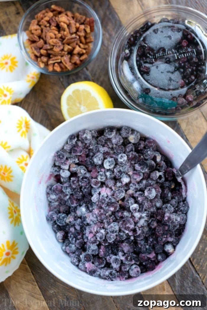 Essential Ingredients for Huckleberry Cobbler A rustic tableau featuring a bowl of fresh huckleberries, a vibrant lemon, and a scattering of pecans on a wooden table, perfectly arranged to inspire a delicious huckleberry cobbler creation.