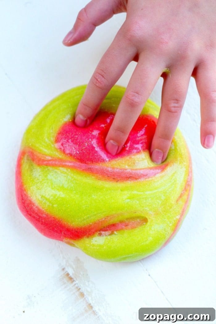 Easy and safe borax-free Elmer's glitter glue slime is perfect for kids' crafts. Child playing with homemade Elmer's glitter glue Christmas slime