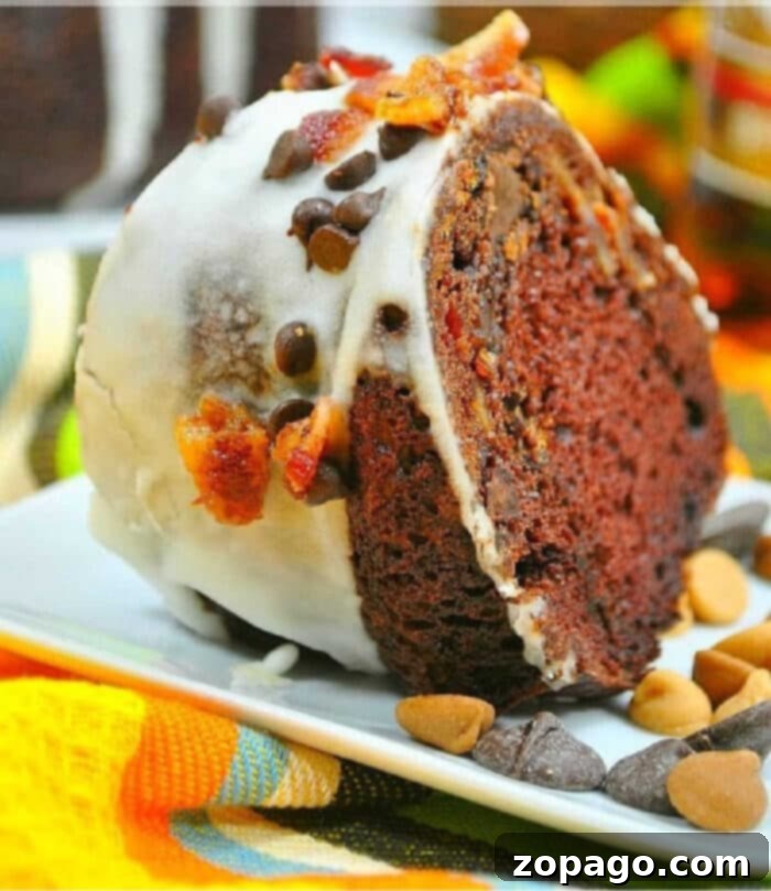 Simple and Spirited Rum Bundt Cake 2 A glistening slice of chocolate rum bundt cake, adorned with white icing, a scattering of chocolate chips, and savory bacon bits, rests invitingly on a pristine white plate.