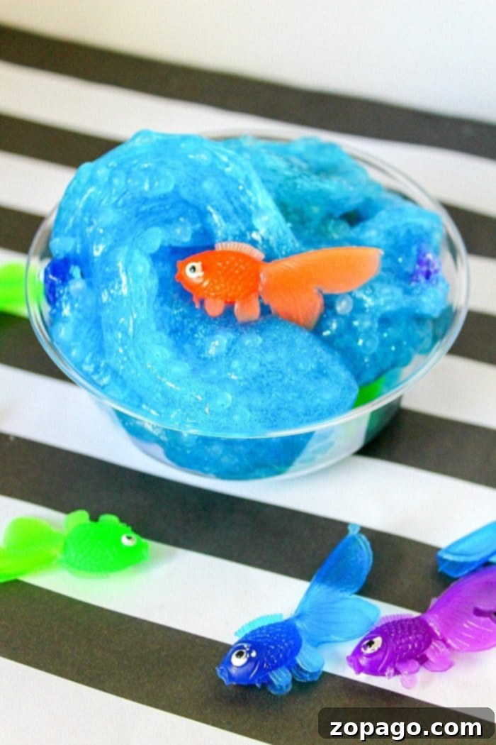 Fun and Safe Borax-Free Fish Slime for Creative Kids Finished borax-free fish slime, stretched and played with, showing its beautiful blue color, fishbowl beads, and plastic fish.