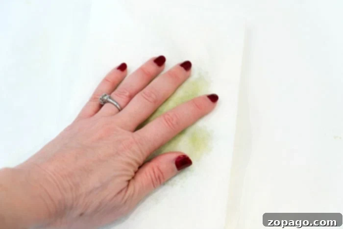 Close-up of shredded zucchini on a paper towel, showing the water being absorbed, illustrating the crucial step for a perfect moist zucchini bread.
