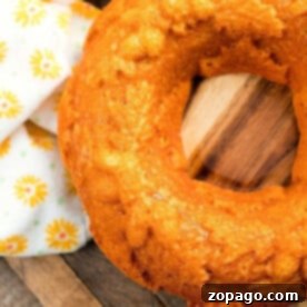 Easy 2 Ingredient Pumpkin Angel Food Cake 7 Close-up of a pumpkin angel food cake slice, elegantly presented on a wooden surface with a decorative floral napkin, highlighting its moist texture and inviting color.