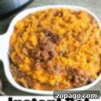 Instant Pot sweet potato casserole in a white dish beside an Instant Pot on a wooden table.