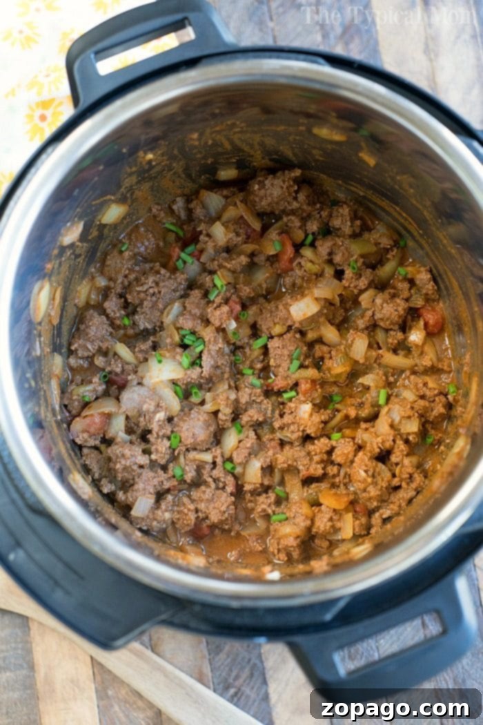 Instant Pot taco meat with onions and tomatoes simmering to perfection, garnished with a sprinkle of fresh green onions.