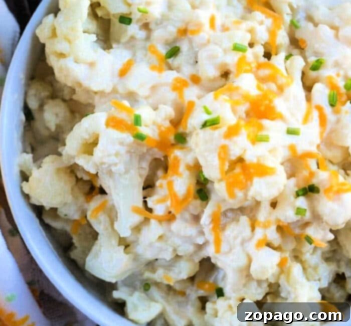 Creamy Cheesy Instant Pot Cauliflower 2 A bowl of effortlessly creamy cheesy cauliflower from the Instant Pot, garnished with fresh shredded cheese and a sprinkle of chopped chives.