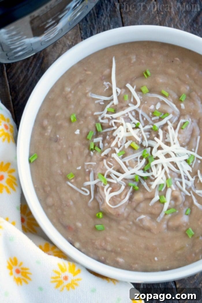 Homemade pressure cooker refried beans recipe that uses no lard and there is no pre soaking required! Perfect addition to burritos or 7 layer dip! #instantpot #refriedbeans #beans #pressurecooker #instantpotrecipes #thetypicalmom #homemade Pressure Cooker Refried Beans in a bowl, ready to be served, showcasing their creamy texture.
