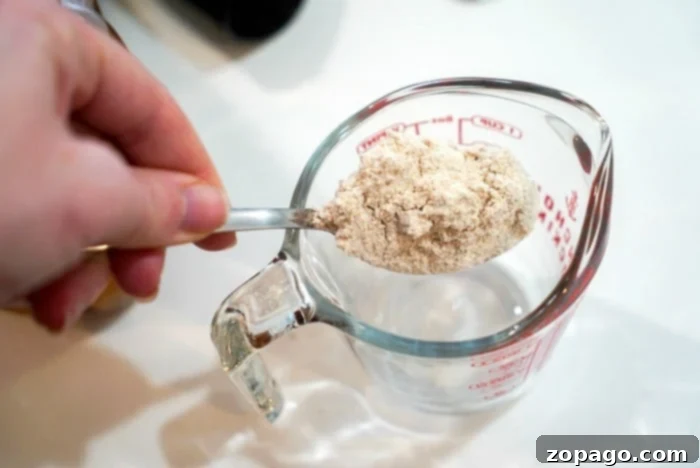 Adding wholesome whole wheat flour to your bread in a bag recipe for a nutritious and delicious loaf. Close-up of whole wheat flour being added to a Ziploc bag for the bread making process.
