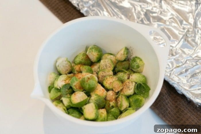 This easy Brussels sprouts recipe is a perfect side dish with a tangy sauce that just makes these vegetables addictive enough to start loving Brussels! #brusselsprouts #baked #best #brussels #mustard #vegetables #sidedish A bowl of seasoned halved Brussels sprouts sits on the kitchen counter, ready to be baked. Wondering how long to bake Brussels sprouts at 450 degrees? They'll become perfectly crispy in about 20-25 minutes.