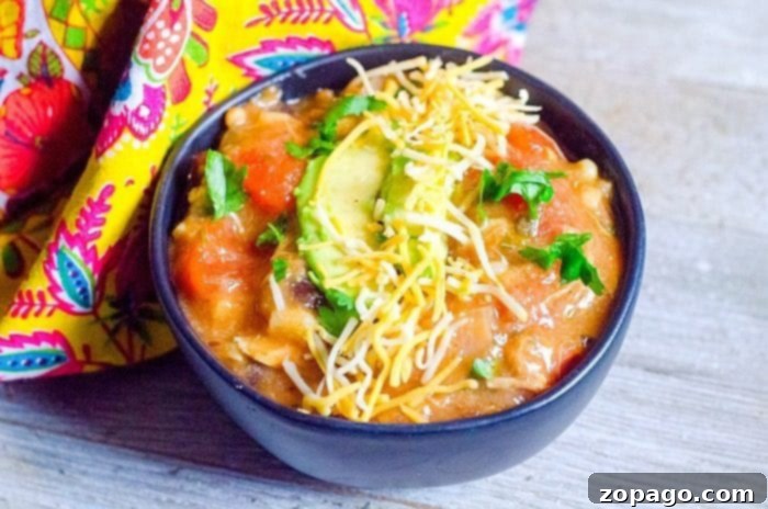 Instant Pot Turkey Chili A bowl of rich Instant Pot Turkey Chili, garnished with fresh cilantro and shredded cheese, served on a dark wooden surface. The chili is thick and hearty, featuring chunks of turkey and beans.