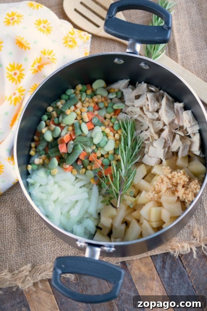 A close-up of creamy turkey pot pie soup simmering in a large pot, with ingredients ready to be added.