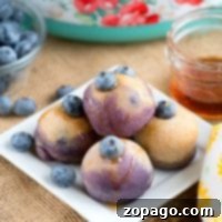 Blueberry pancake bites on a square white plate, garnished with fresh blueberries and drizzled with syrup, resemble delightful Instant Pot pancake bites that elevate any breakfast spread.