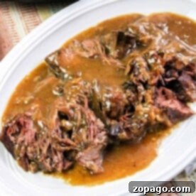 Tender Pressure Cooker Roast Beef 3 Tender pot roast, cooked to perfection in a pressure cooker, is smothered in gravy on a white plate, served on a striped tablecloth.