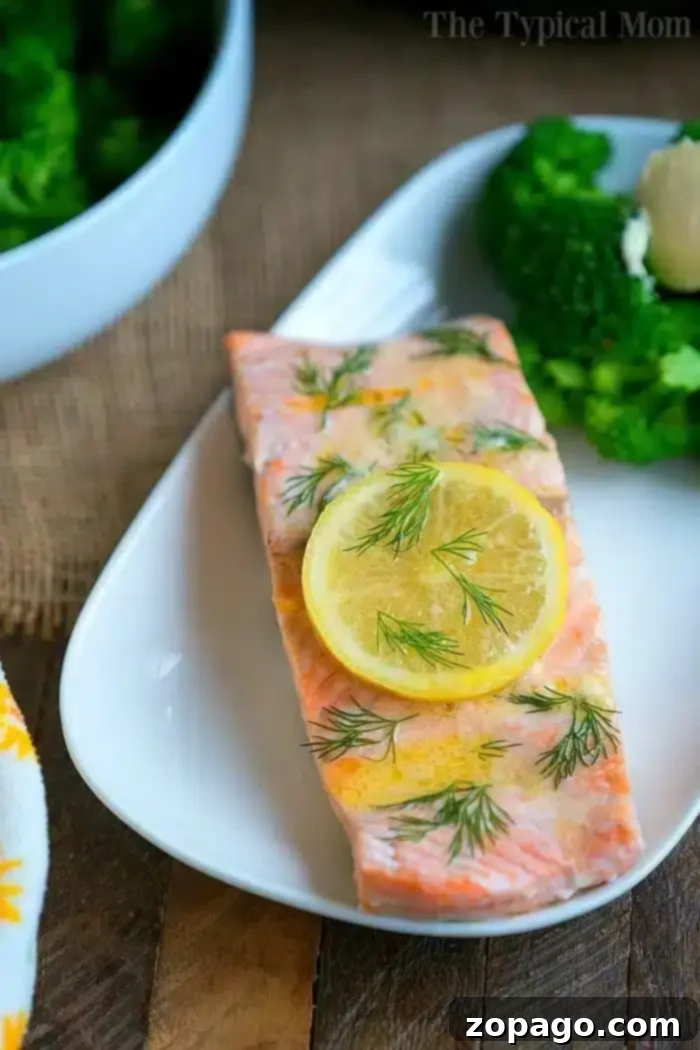 Delicious Pressure Cooker Salmon with Broccoli A perfectly cooked piece of salmon, enhanced by pressure cooker fish recipes, garnished with a lemon slice and fresh dill, served alongside steamed broccoli.