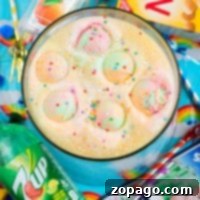 A colorful rainbow punch, crafted from a lively party punch recipe, features ice cream scoops and sprinkles, surrounded by various snacks and drinks. This vibrant beverage is the centerpiece of a joyful celebration, inviting everyone to enjoy its festive flavors.