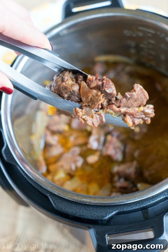 French onion pressure cooker roast is tender with tons of flavor. Perfect Instant Pot shredded beef tacos for dinner even your kids will rave about. Close-up of a French onion beef being served with tongs from a pressure cooker.