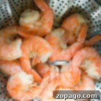 Steamed shrimp cooked to perfection in an Instant Pot, nestled in a metal basket with a perforated design.