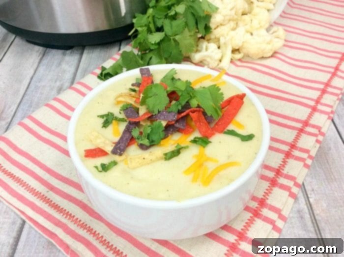Instant Pot cauliflower soup is a creamy and delicious low carb meal our whole family loves! Easy to throw together keto soup you'll make again and again. Instant Pot cauliflower soup with a spoon