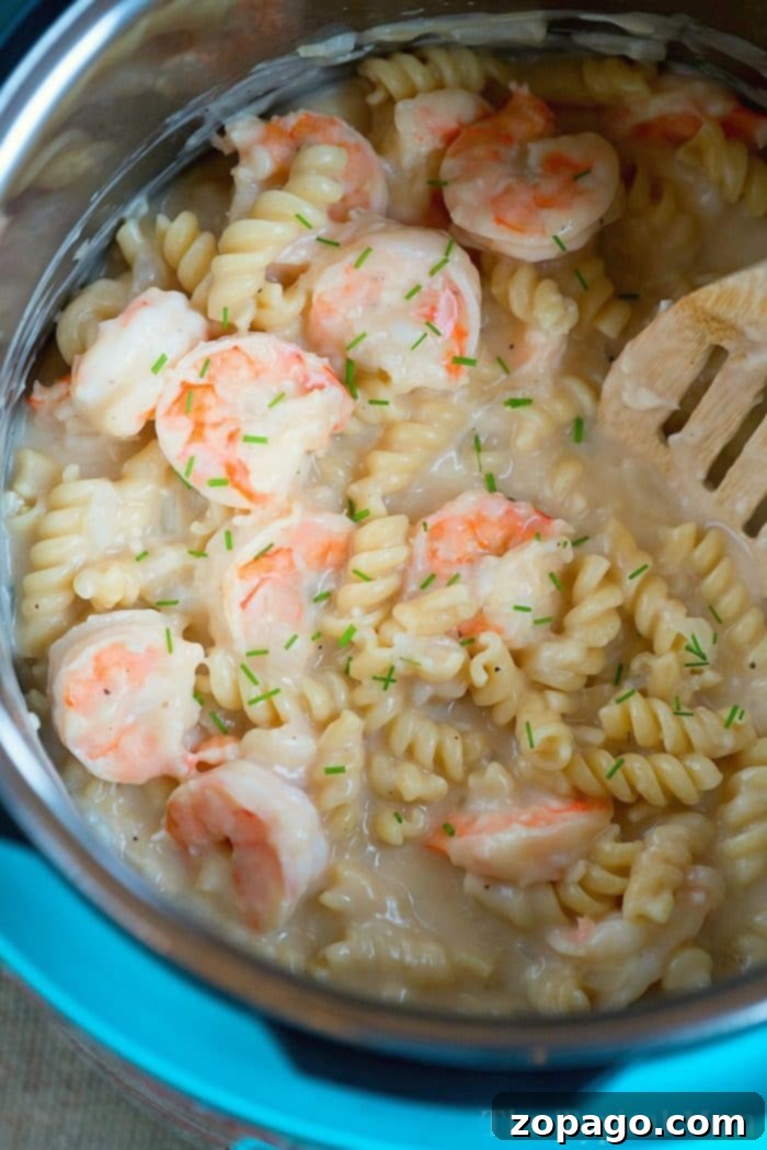 A close-up shot of Instant Pot Shrimp Alfredo pasta, showing the creamy sauce, plump shrimp, and pasta noodles, garnished with herbs.
