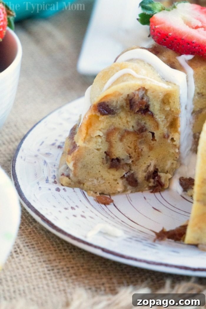 Instant Pot bread pudding is one of our favorite pressure cooker dessert recipes! Moist and pretty in a bundt pan it will become a favorite of yours too. A slice of decadent bread pudding with white icing sits gracefully on a decorative plate, crowned with sweet strawberry slices—a delightful treat that rivals even the richest instant pot bread pudding.