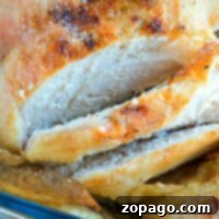 Close-up of a pressure cooker beer can chicken with golden, crispy skin and slices revealing tender, juicy white meat.