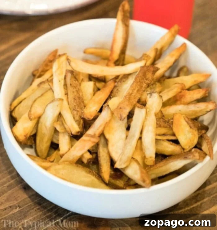 Ninja Foodi Perfect Crispy French Fries 6 A beautifully presented bowl of golden-brown homemade French fries, perfectly crisped using the Ninja Foodi, sits invitingly on a rustic wooden table, ready to be enjoyed.