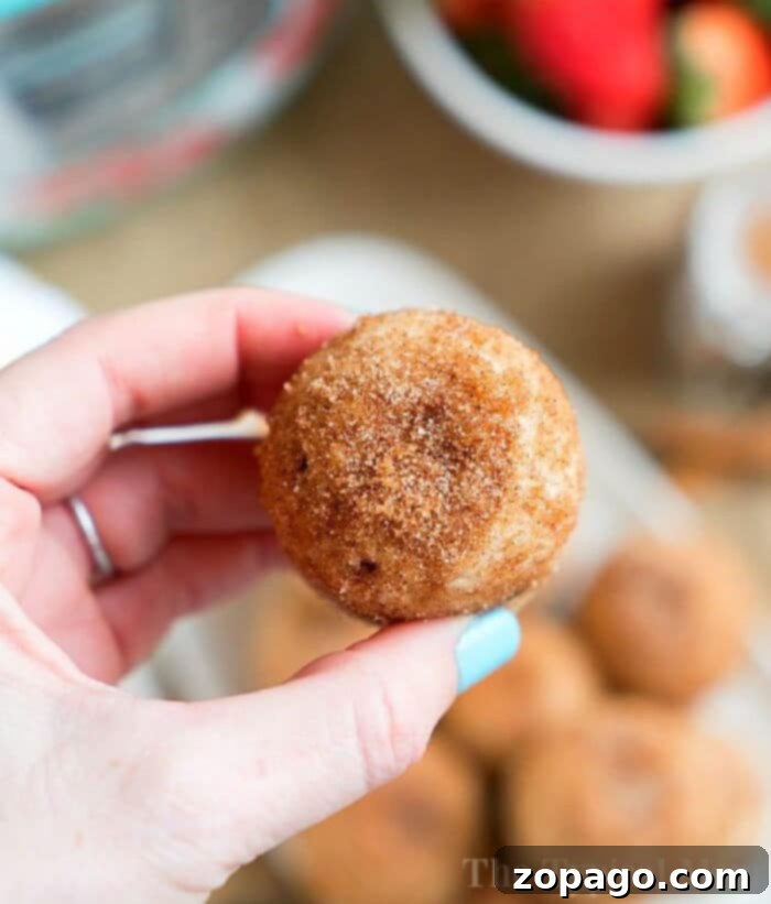 Crispy Instant Pot Churro Bites 2 Close-up of golden brown Instant Pot churro bites generously coated in cinnamon sugar, resting on a white surface, showcasing their delicious texture and inviting appearance.