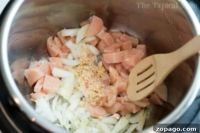 Pressure cooker chicken pot pie soup is a spoonful of comfort food made in under 15 minutes! You've got to try this creamy chicken soup with veggies today. #instantpotrecipes #pressurecooker #chickenpotpie #soup #chickensoup #ninjafoodirecipes #crockpotexpressrecipes #thetypicalmom A close-up of creamy chicken pot pie soup cooking in a pressure cooker, with steam gently rising.