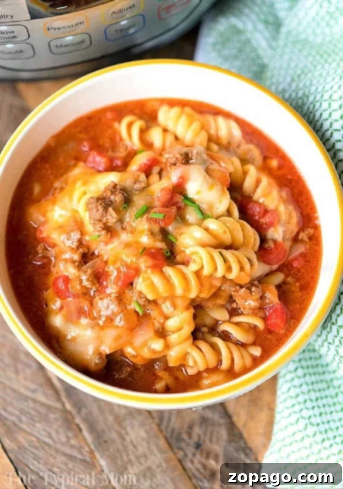 Ninja Foodi One-Pot Taco Pasta 2 Ninja Foodi taco pasta in a bowl with melted cheese and fresh herbs, ready to serve.