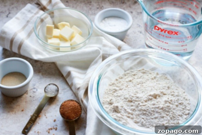 Crispy Air Fryer Pretzel Bites 4 Ingredients for air fryer pretzel bites laid out on a wooden board: flour, yeast, brown sugar, salt, water, and melted butter.